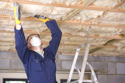 Man wearing protective mask and installing ceiling insulation